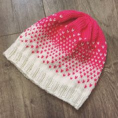 a red and white knitted hat sitting on top of a wooden floor