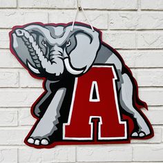 an elephant with the letter a painted on it's face is hanging from a brick wall