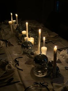 there are many candles on the table with dishes and silverware around it, all lit up