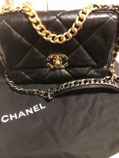 This is an authentic CHANEL Lambskin Quilted Medium Chanel 19 Flap in Black. This pillowy soft shoulder bag is crafted of oversized quilted goatskin leather in black. The refined bag features a chain detail CC turn-lock on the flap, a magnetic snap pocket on the back, a chunky matte gold chain top handle, and a leather threaded gradient gold to ruthenium chain-link shoulder strap. The front flap opens to a red fabric interior with a pocket. THIS ITEM IS FINAL SALE! Size Base length: 9.5 in Heigh High-end Black Quilted Bag, Black Quilted Shoulder Bag For Everyday Luxury, Luxury Quilted Flap Bag, Luxury Quilted Flap Bag With Top Handle, Luxury Quilted Top Handle Flap Bag, Black Quilted Leather Flap Bag, Designer Black Quilted Flap Bag, Designer Quilted Black Flap Bag, Black Quilted Flap Bag For Evening