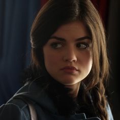 a close up of a person wearing a blue jacket and looking at the camera with an intense look on her face