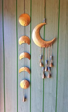 a wooden wall with three moon and bells hanging from it