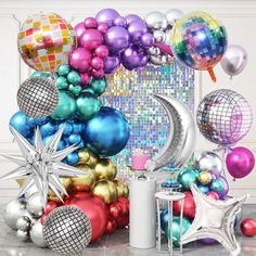 there are many balloons and decorations on the floor in front of a wall with disco balls