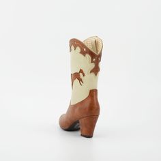 1950's Inspired Bucking Horse Adorned Western Boots. Proud To Be 100% Vegan Friendly. Upper Material: Faux Textured Leather Lining: Man Made + Fabric Step In Boot w/ Inner Tab For Easy Access. Heel Height: 3" Inches Approximate Shaft Height: (based on size 6 from top to back counter) 7 1/2" Inches / Mid Calf Height Fits True To Size, Please Size Up 1/2 If You Take A Wider Width. For Any Sizing Suggestions, Please Contact Customer Care. Imported Retro Brown Boots For Spring, Brown Retro Boots For Spring, Vintage Brown Boots For Spring, Vintage Fitted Heeled Boots For Rodeo, Vintage Heeled Boots With Round Toe For Spring, Vintage Round Toe Heeled Boots For Spring, Retro Fall Heeled Boots, Retro Fitted Boots For Rodeo, Retro Heeled Boots For Fall Formal Events