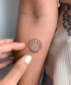 a woman with a shell tattoo on her arm