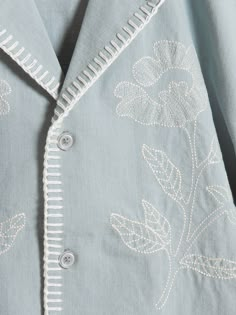 an embroidered blue shirt with white flowers on the front and back, along with buttons