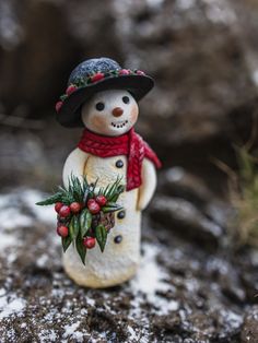 a snowman figurine wearing a hat and scarf on top of a rock