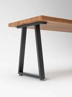 a wooden table with black metal legs and a white wall in the backround