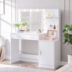 a white vanity table with lights on it and a plant in front of the mirror