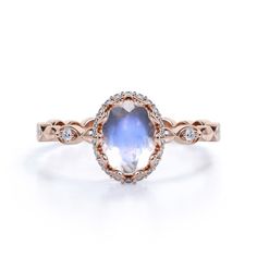 an oval blue and white sapphire ring with diamonds on the band, set in rose gold