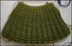 a green purse sitting on top of a table next to a pair of knitting needles