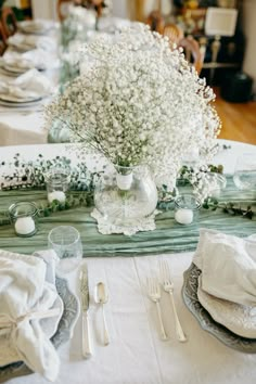 the table is set with silverware and baby's breath flowers