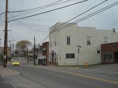 a yellow car is parked on the side of the road in front of an old building