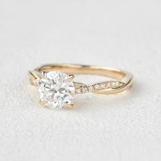 a gold engagement ring with a round diamond on the side and pave set diamonds around the band