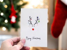 a hand holding up a card with a reindeer's head on it and the words merry christmas