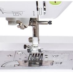 the sewing machine is on top of the white surface with green ball in it's center