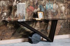 a table that is sitting on the ground in front of a wall with pictures and paintings