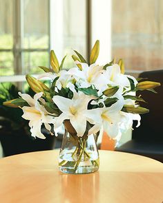 a vase filled with white flowers on top of a wooden table