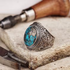 Immerse yourself in the beauty of authentic craftsmanship with our handcrafted silver ring, enriched with a genuine turquoise stone and adorned with traditional motifs. The oval mount harmoniously embraces the turquoise, creating a centerpiece that is both captivating and meaningful. Every detail of this ring tells a story of tradition, enhancing its charm and making it a treasure in your jewelry collection. It's more than a ring; it's a celebration of artistry and the natural beauty of turquois Artisan Turquoise Ring, Southwestern Style Engraved Turquoise Ring As Gift, Engraved Southwestern Style Turquoise Ring For Gift, Artisan Turquoise Ring With Patina, Bohemian Engraved Turquoise Ring In Sterling Silver, Artisan Turquoise Gemstone Ring, Artisan Turquoise Oval Cabochon Ring, Bohemian Engraved Turquoise Ring For Gift, Artisan Oval Ring With Patina