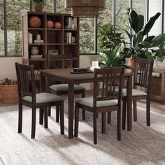 a dining room table and chairs in front of a large window with potted plants