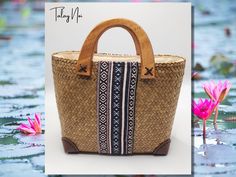 Elevate your style with this exquisite handcrafted bag made from Krajood, a unique plant found in the picturesque region of Phattalung, Thailand. Carefully woven by skilled artisans, this bag seamlessly blends traditional Thai craftsmanship with contemporary design. ----- Dimensions: Height: 22cm (31cm including handle) Width: 29cm Depth: 12cm ----- The front and back of the bag feature strips of authentic Thai fabric, adding a touch of culture and elegance to your ensemble. The wooden hoop hand Traditional Handheld Shoulder Bag For Summer, Traditional Rectangular Vacation Bag, Traditional Rectangular Vacation Bags, Traditional Top Handle Bag In Natural Color, Rectangular Straw Bag With Leather Handles As Gift, Summer Bags With Leather Handles As Gift, Summer Bags With Leather Handles For Gift, Traditional Natural Color Top Handle Bag, Traditional Rectangular Bags For Summer