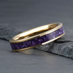 two gold wedding bands with amethyst purple stone inlays on top of each other