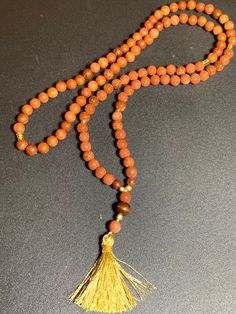 This lovely mala is made up of a combination of 8mm Goldstone and Rosewood beads, a 10mm wood guru bead and a coordinating handmade tassel. Goldstone is associated with confidence and self-empowerment believed to enhance self-esteem and inner strength, and offer support for overcoming self-doubt or insecurities. Goldstone carries an uplifting energy, promoting a positive attitude and dispelling negative thoughts or emotions. It supports focus, concentration, and mental clarity, and helps with de Brown Natural Stones Mala As A Gift, Traditional Rosary With Gemstone Beads For Healing, Brown Hand Knotted Mala As Gift, Rosary With Natural Stones For Meditation, Brown Mala With Natural Stones And Round Beads, Spiritual Rosary With Round Beads For Meditation, Spiritual Rosary For Meditation With Round Beads, Adjustable Natural Stones Rosary For Meditation, Bohemian Rosary With 108 Beads For Healing