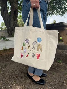 LIMITED EDITION- ONLY 8 AVAILABLE The summer tote or beach bag of your dreams is HERE! Icons of el Verano that bring summer vibes to any season☀️ 100% Cotton/ Multicolor design Embroidered with love by JZD in Brownsville, TX Pocket inside Measurements Tote bag: 14" x 14"  Depth: 5.5" Handles: 11" Trendy Embroidered Canvas Bag For Travel, Summer Embroidered Shopping Bags, Summer Embroidered Shoulder Bag For Shopping, Trendy Embroidered Summer Bag, Casual Embroidered Beach Bag, Embroidered Shoulder Bag For Summer Shopping, Summer White Embroidered Canvas Bag, Canvas Shopping Bags For Summer, Trendy Embroidered Shoulder Bag For Summer