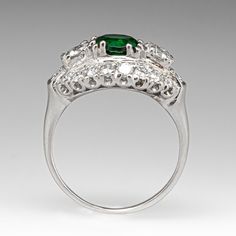 This gorgeous vintage ring is centered with one (1) round cut natural Tsavorite garnet set into a four-split prong setting. The Tsavorite is flanked to each side by one (1) prong set old European cut diamond. The ring is also bordered with eighteen (18) bead and prong set round brilliant cut diamonds. The ring measures 11.6mm at the top, rises 6.8mm above the finger, and tapers to 1.5mm wide by 0.8mm thick at the base of the shank. It is crafted in platinum and is currently a size 6. One of the accents diamonds is lightly chipped. Tsavorite Garnet Ring, Tsavorite Garnet, Garnet Ring, European Cut Diamonds, Garnet Rings, Vintage Ring, One 1, Round Brilliant Cut Diamond, Round Brilliant Cut