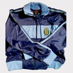 Premium Argentina Football Jacket Fitted Blue Track Jacket For Streetwear, Vintage Blue Long Sleeve Track Jacket, Blue Fitted Sporty Windbreaker, Blue Long Sleeve Sport Coat, Blue Fitted Casual Windbreaker, Retro Blue Track Jacket With Pockets, Vintage Blue Track Jacket With Pockets, Retro Blue Hooded Track Jacket, Vintage Blue Outerwear For Sports