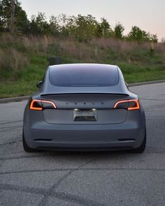 an electric car is parked on the side of the road in front of some grass