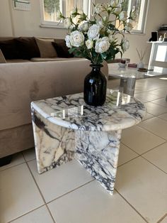 a marble table with flowers on it in front of a couch