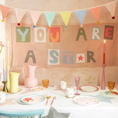 a table with plates and cups on it in front of a banner that says you are a star