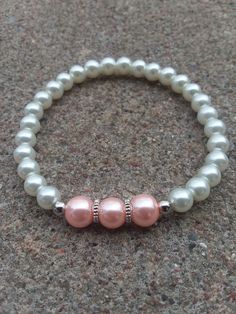 This elegant bracelet is made with white, pink, and silver beads, silver cogwheel spacers, and stretch cord. These would make lovely accessories to weddings, Easter celebrations, or any other special occasion! They also make beautiful gifts! If ordering for a child, please put so in the note section when checking out and the age of the child (bracelets shown in pictures are adult sizes). *If your wrist runs small, either message me or put something in the comment section of your purchase order to make it a little smaller* *Remember to roll stretch bracelets over the hand to preserve shape and elasticity and reduce stretching out to much* *The goal of my shop is to make available elegant, beautiful jewelry that anyone can afford so all items are $15 and under! If you see an item you like bu Adjustable White Charm Bracelet With Silver Beads, White Pearl Bracelet With Spacer Beads For Wedding, White Beaded Bracelets With Spacer Beads For Wedding, White 8mm Beads Bracelets For Wedding, White 8mm Beaded Bracelets For Wedding, White 8mm Beads Bracelet For Wedding, White Beaded Bracelet, White Beads Bracelet, Wedding Bracelets