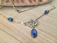 Length : 43 cm  Antiqued brass Art Nouveau inspired lily stamping, replica of Guyot stamping : 30x20 mm Sodalite cabochon in Victorian style antiqued brass setting : 14x10 mm Montana blue faceted glass cabochons : 10x8 mm. Glass cabs are faceted in Germany, settings are US made. Nickel free, lead free, cadmium free antiqued brass necklace Jewelry designer necklace© Tracked shipping within 24 hours, ready to gift For more info, please, do not hesitate to DM me AG/ByAtelierDeLaColline© Vintage Brass Necklaces With Cabochon, Antique Gold Cabochon Necklace, Blue Brass Jewelry With Vintage Charm, Blue Brass Necklace With Vintage Charm, Antique Gold Necklace With Cabochon, Antique Brass Jewelry With Cabochon, Antique Bronze Necklace With Cabochon, Antique Gold Cabochon Brass Necklace, Antique Gold Brass Necklace With Cabochon