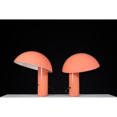 two orange mushroom shaped lamps sitting on top of a white table next to each other