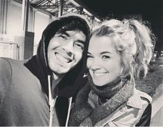 black and white photo of two people smiling for the camera, one is wearing a hoodie