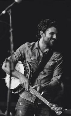 a man playing a guitar while standing next to a microphone