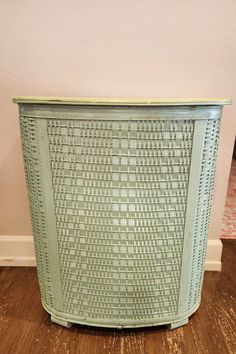 a green basket sitting on top of a wooden floor