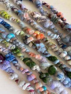 multicolored skeins of yarn are arranged in rows on a white surface