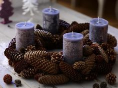 three lit candles sitting on top of pine cones