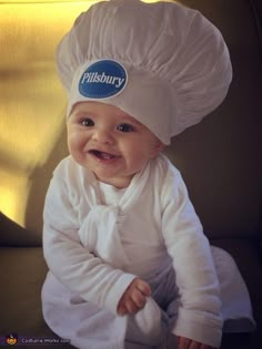 a baby wearing a chef's hat sitting on top of a brown chair with the words pillsbury written on it