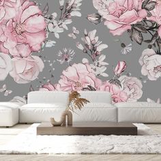 a white couch sitting in front of a wall with pink flowers on it