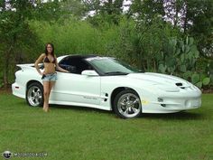 a woman standing next to a white sports car