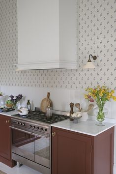 a stove top oven sitting inside of a kitchen next to a wallpapered wall