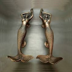 two bronze mermaid figurines sitting next to each other