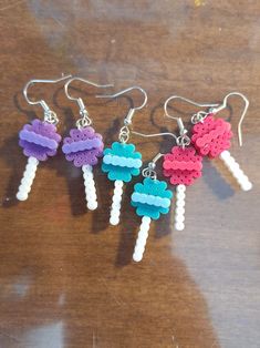 three different colored ice cream earrings on top of a wooden table