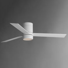 a white ceiling fan with a light on it's side and a gray wall in the background