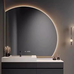 a bathroom with a round mirror and lights on the wall above it, along with two vases