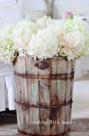 a wooden barrel with flowers in it sitting on the floor next to a white chair